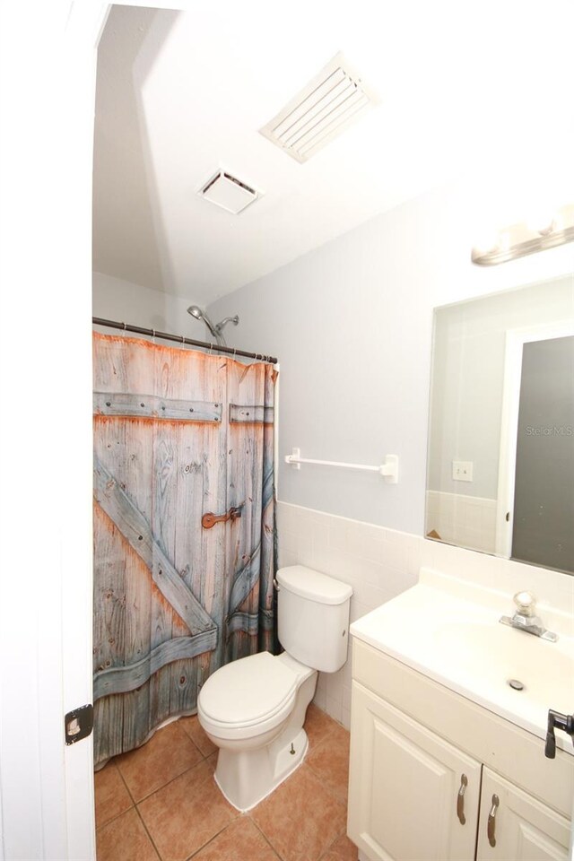 bathroom featuring tile walls, visible vents, tile patterned flooring, and wainscoting