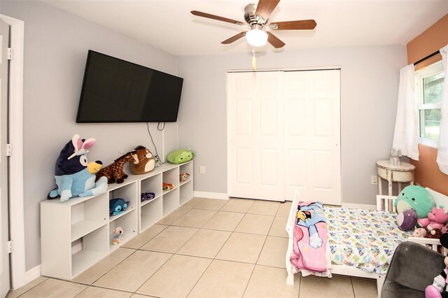 bedroom featuring a ceiling fan, light tile patterned flooring, baseboards, and a closet