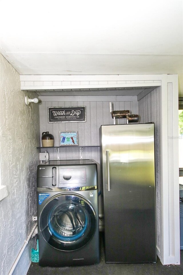 laundry room featuring washer / clothes dryer, a textured wall, and laundry area