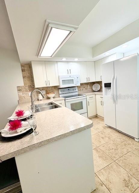 kitchen featuring white appliances, light countertops, white cabinetry, a sink, and backsplash