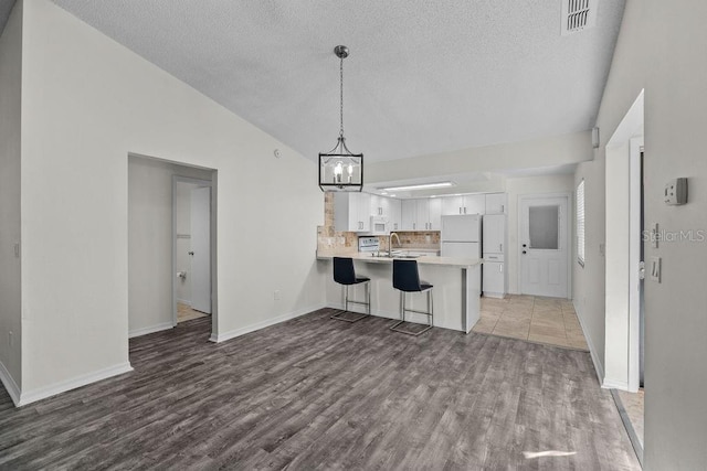 interior space with a textured ceiling, vaulted ceiling, wood finished floors, a sink, and a chandelier