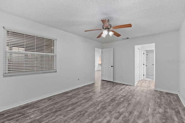 unfurnished bedroom featuring a ceiling fan, a textured ceiling, visible vents, wood finished floors, and baseboards