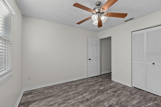 unfurnished bedroom featuring a textured ceiling, baseboards, wood finished floors, visible vents, and a closet