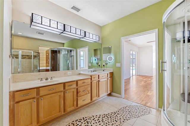 bathroom featuring a sink, tile patterned flooring, double vanity, visible vents, and a stall shower