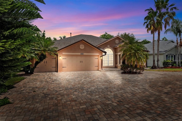 view of front of house with a garage, stucco siding, and decorative driveway
