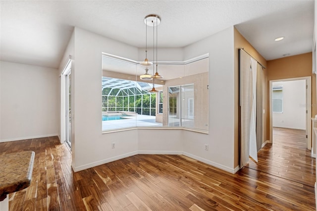 unfurnished dining area featuring wood-type flooring and baseboards