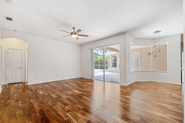 unfurnished living room with a ceiling fan, a textured ceiling, visible vents, and wood finished floors