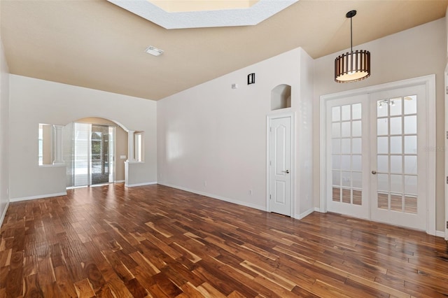interior space featuring baseboards, arched walkways, a skylight, and hardwood / wood-style floors