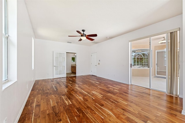 spare room with baseboards, ceiling fan, visible vents, and wood finished floors