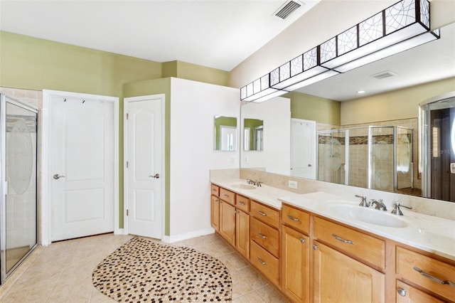 bathroom with double vanity, visible vents, a stall shower, a sink, and tile patterned floors