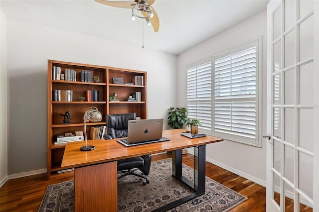home office with dark wood-style flooring, a ceiling fan, and baseboards