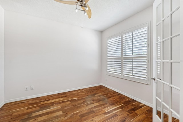 spare room featuring a ceiling fan, baseboards, wood finished floors, and a textured ceiling