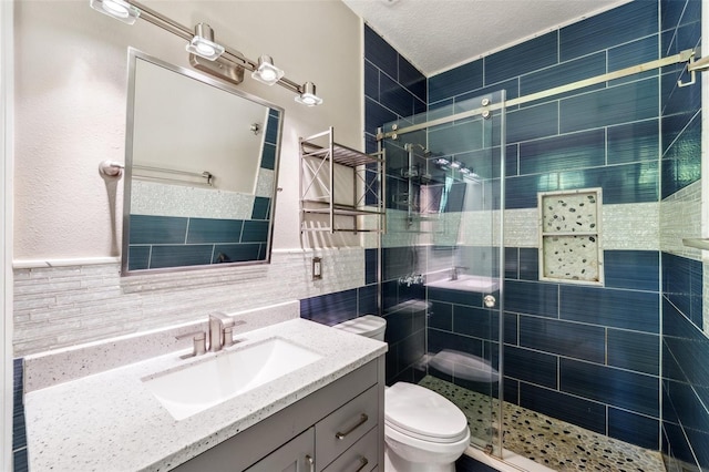 full bathroom with vanity, a shower stall, toilet, and tile walls