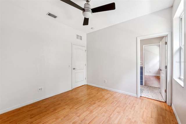 unfurnished bedroom with visible vents, connected bathroom, baseboards, and light wood-type flooring