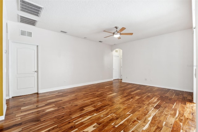 spare room featuring arched walkways, ceiling fan, wood finished floors, and visible vents
