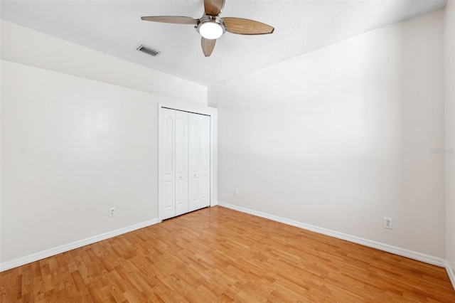 spare room featuring baseboards, ceiling fan, light wood finished floors, and visible vents
