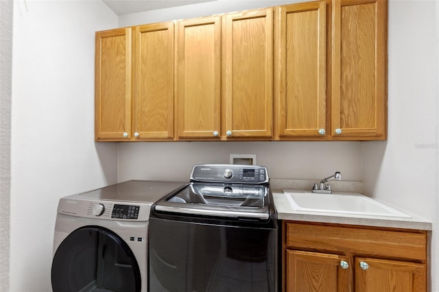 washroom with a sink, cabinet space, and washer and dryer