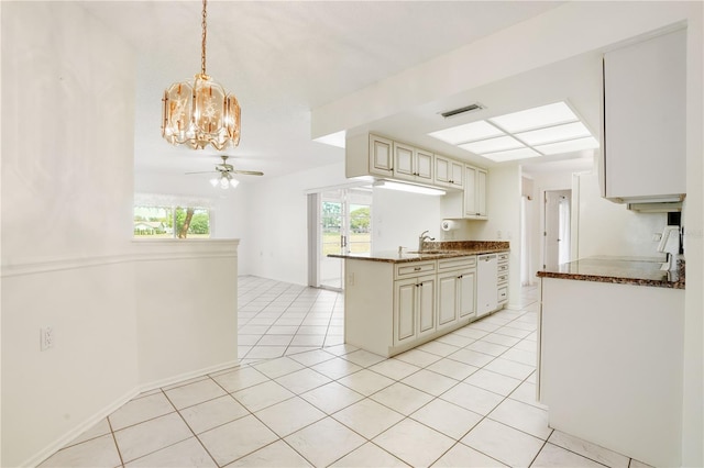 kitchen with cream cabinetry, a sink, light tile patterned floors, and ceiling fan with notable chandelier