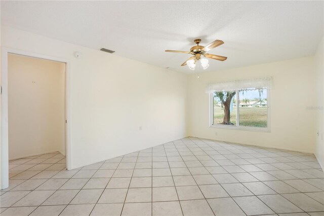 spare room featuring a ceiling fan, light tile patterned flooring, and visible vents