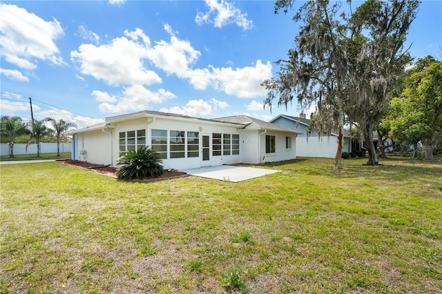 rear view of property with a sunroom, stucco siding, a patio area, and a lawn