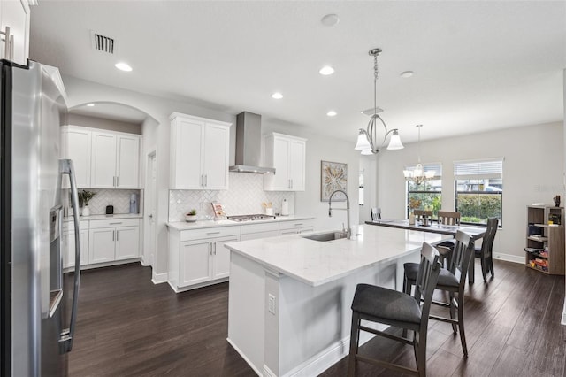 kitchen featuring dark wood finished floors, wall chimney exhaust hood, decorative backsplash, and stainless steel appliances