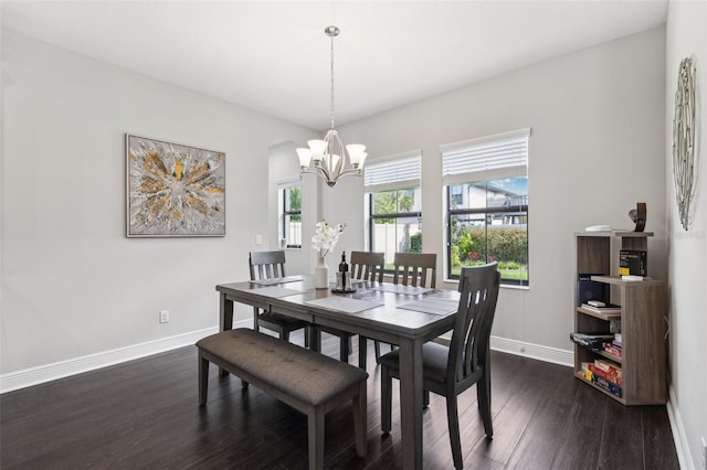 dining space featuring dark wood-style flooring, a notable chandelier, and baseboards