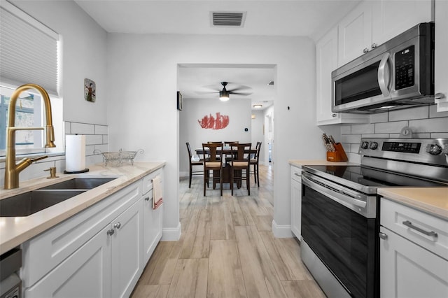 kitchen featuring a sink, tasteful backsplash, visible vents, a ceiling fan, and appliances with stainless steel finishes