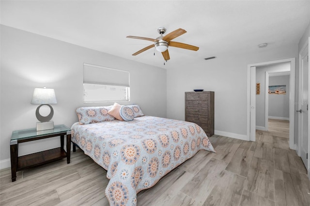 bedroom featuring baseboards, visible vents, wood finished floors, and a ceiling fan