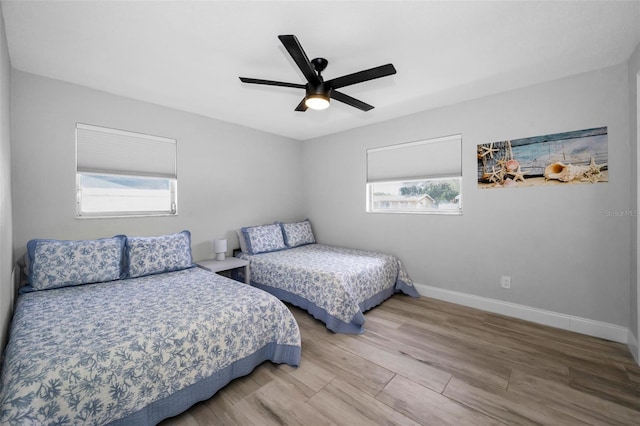 bedroom featuring baseboards, multiple windows, ceiling fan, and wood finished floors