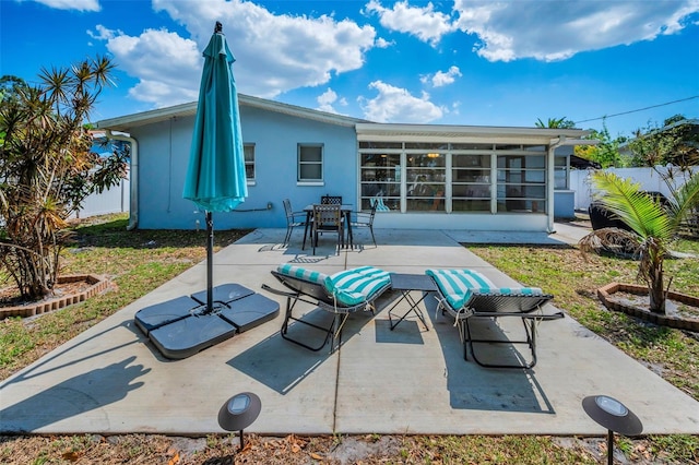 back of property with outdoor dining space, fence, a patio, stucco siding, and a sunroom