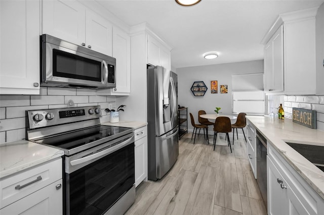 kitchen with stainless steel appliances, backsplash, and white cabinets