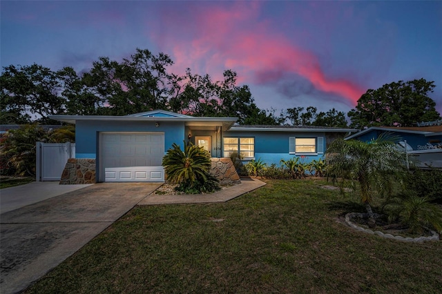 single story home featuring a front lawn, stucco siding, an attached garage, and concrete driveway