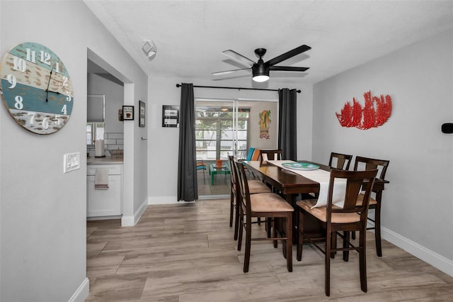 dining area with a ceiling fan, baseboards, and light wood-style flooring