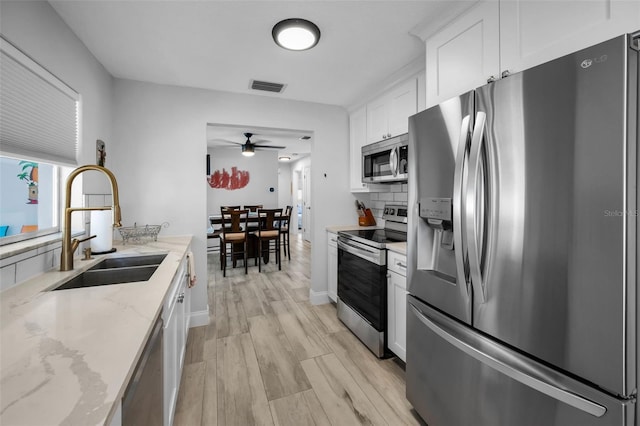 kitchen with a ceiling fan, light wood finished floors, visible vents, a sink, and appliances with stainless steel finishes