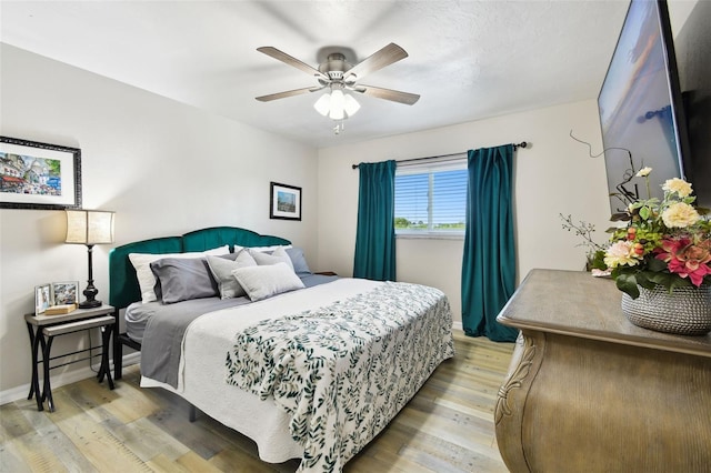 bedroom with light wood-style floors, baseboards, and a ceiling fan