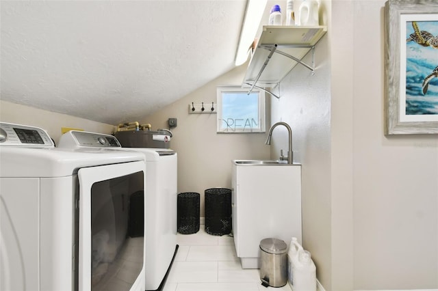laundry room featuring a textured ceiling, light tile patterned flooring, a sink, washing machine and clothes dryer, and laundry area