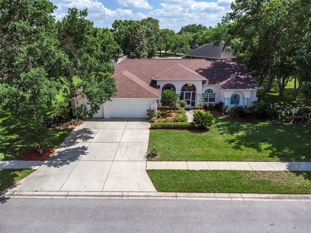 mediterranean / spanish-style home featuring driveway, roof with shingles, stucco siding, a front lawn, and a garage