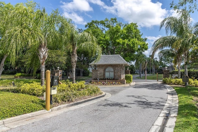 view of road featuring a gated entry, a gate, and curbs