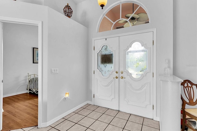 foyer entrance featuring light tile patterned flooring, baseboards, and french doors