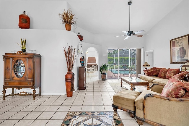 living area with light tile patterned flooring, high vaulted ceiling, baseboards, arched walkways, and ceiling fan