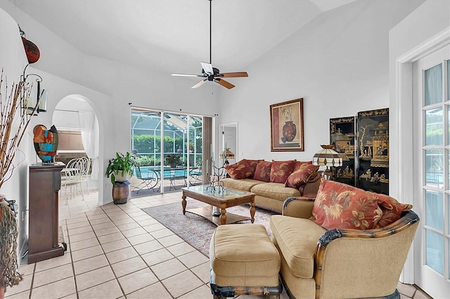 living room featuring light tile patterned flooring, a sunroom, arched walkways, and a ceiling fan