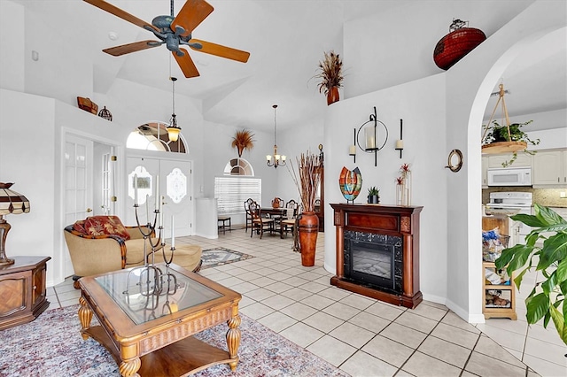 living room featuring arched walkways, a ceiling fan, light tile patterned floors, and a towering ceiling