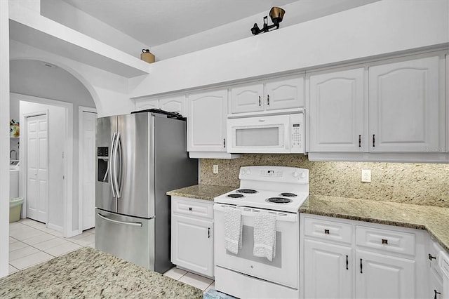kitchen featuring light tile patterned flooring, white appliances, light stone counters, and white cabinets
