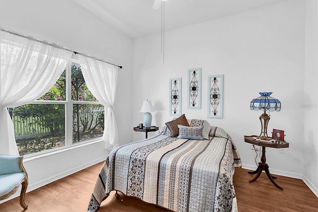 bedroom featuring baseboards, wood finished floors, and ceiling fan