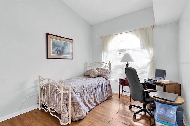 bedroom with baseboards, vaulted ceiling, and wood finished floors