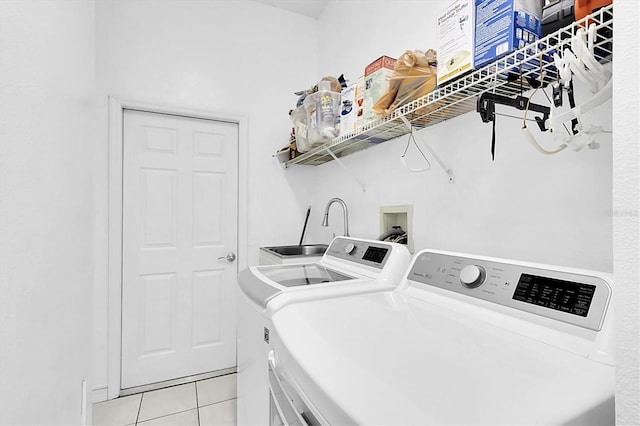 clothes washing area featuring light tile patterned flooring, separate washer and dryer, and laundry area