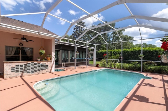 pool featuring a ceiling fan, glass enclosure, and a patio area