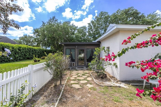 property entrance featuring stucco siding and fence