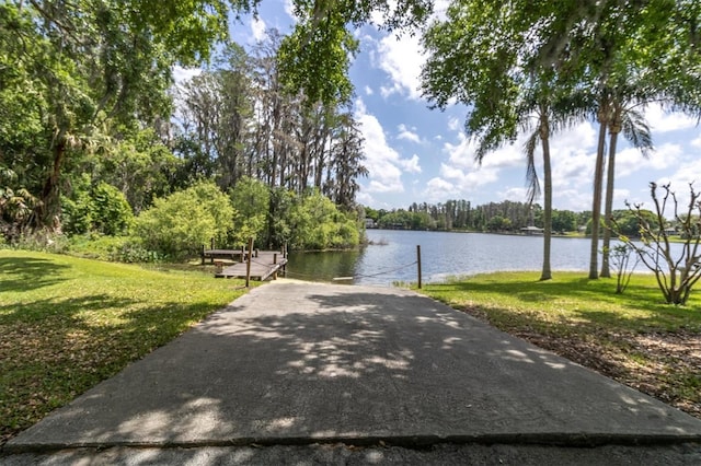 surrounding community featuring a lawn, a water view, and a boat dock