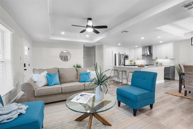 3416 Lema Dr, Spring Hill, FL 34609 - living area with light wood finished floors, visible vents, a ceiling fan, and a raised ceiling
